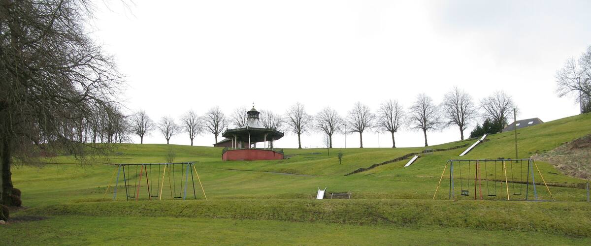 A park with a gazebo, swings, and a grassy hill.