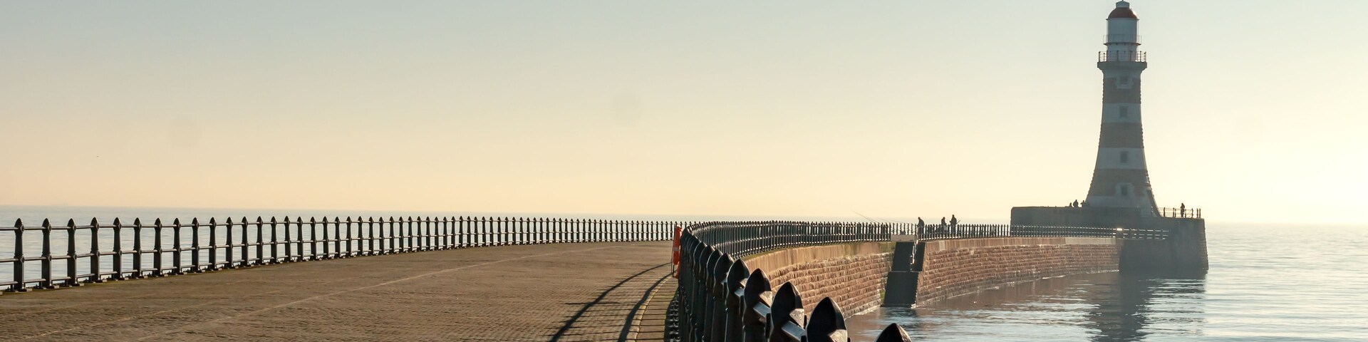 A coastal walkway with a lighthouse in the distance.