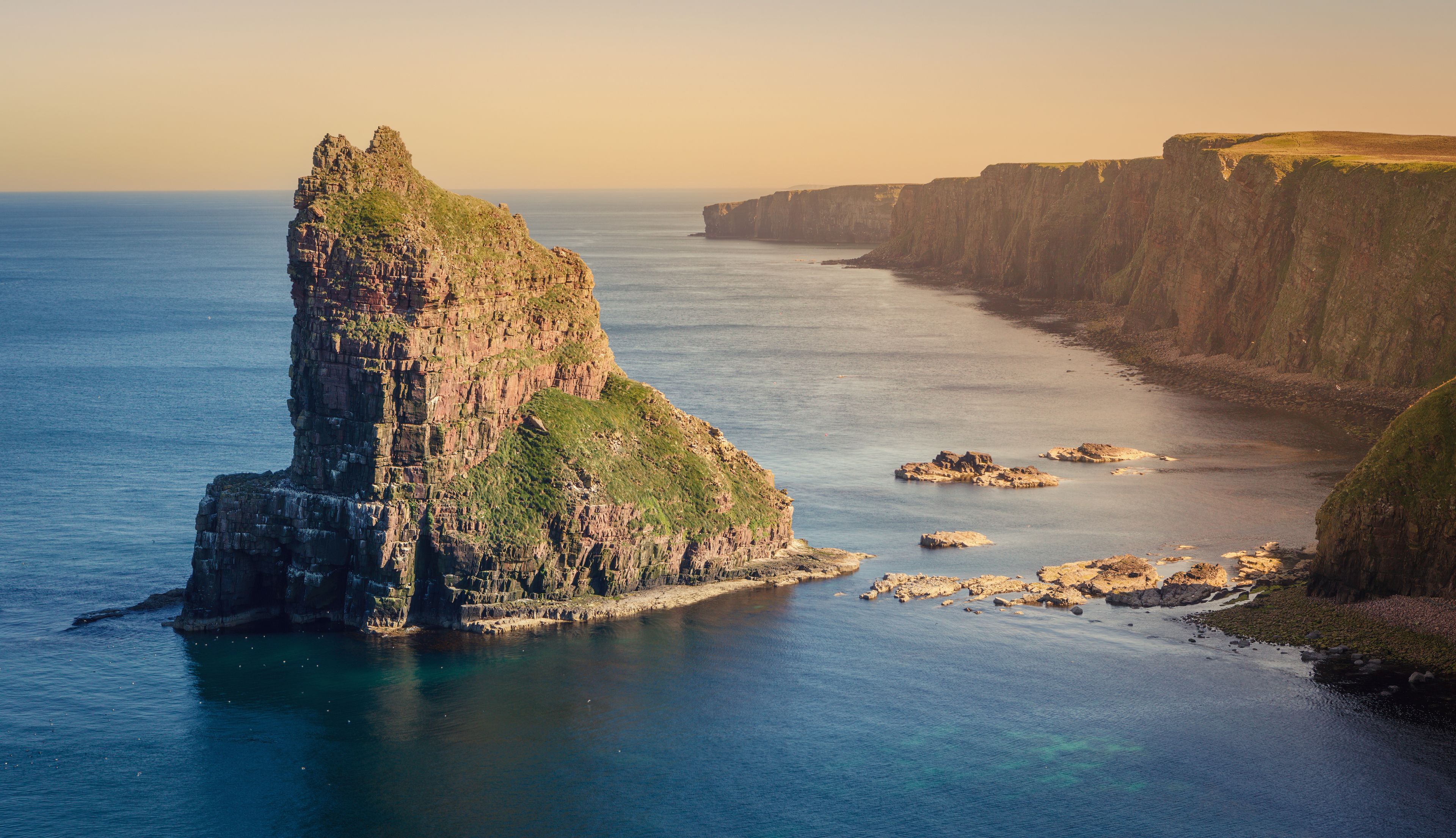 A coastal landscape with a prominent rock formation and cliffs.