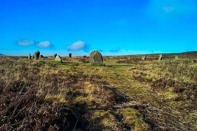 A field of standing stones under a clear blue sky.