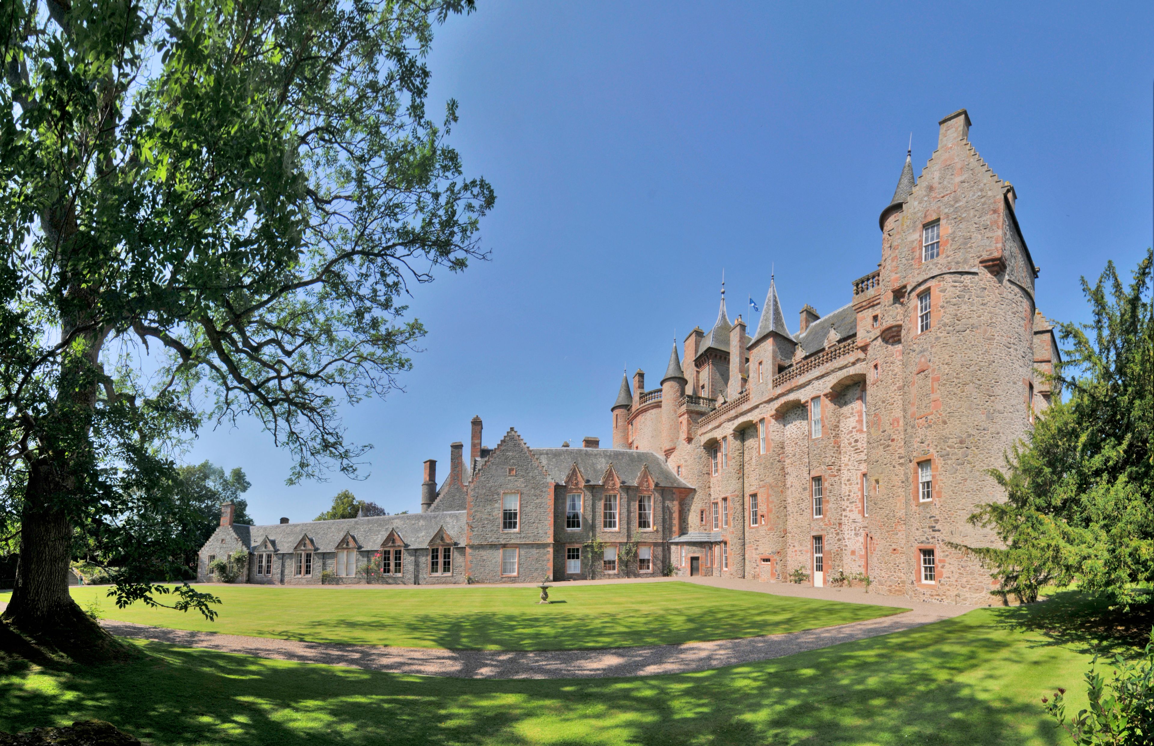 A large stone castle with multiple towers and a well-maintained lawn.