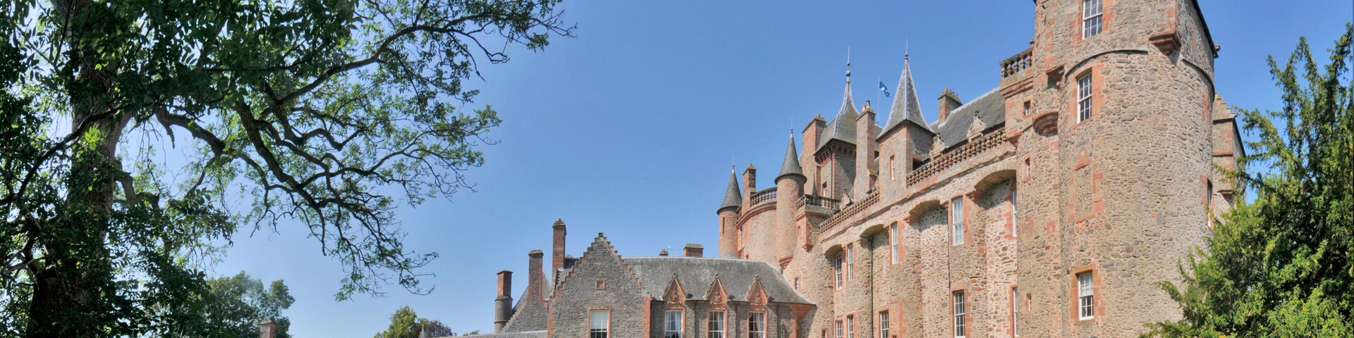 Eine große Steinschlossburg mit mehreren Türmen und einem gepflegten Rasen.