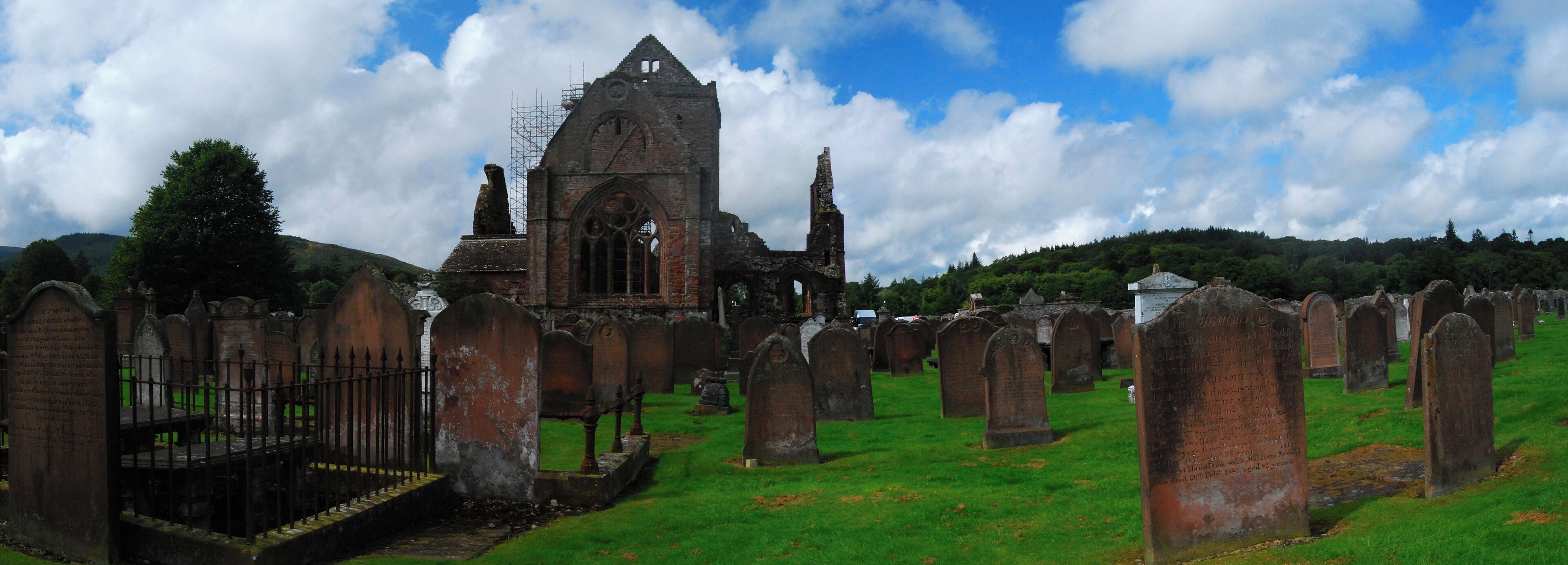 An ancient church with a tall spire, surrounded by a cemetery with numerous headstones.