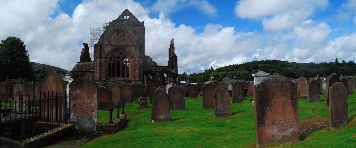 An ancient church with a tall spire, surrounded by a cemetery with numerous headstones.