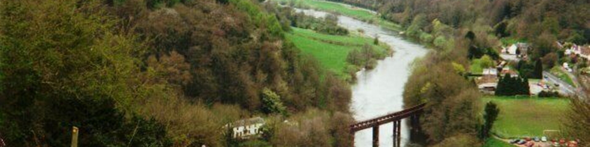 Un río serpentea por un valle con un puente, rodeado de colinas y vegetación.