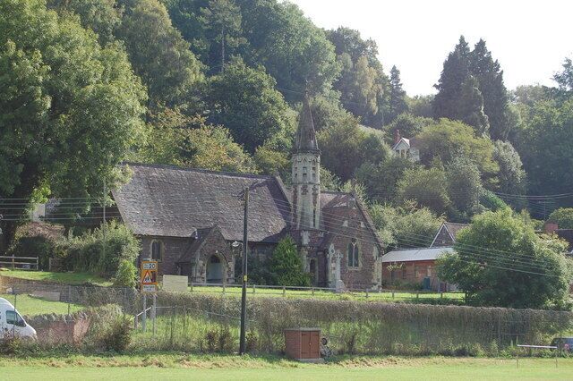 A church with a steeple, surrounded by trees and a grassy area.