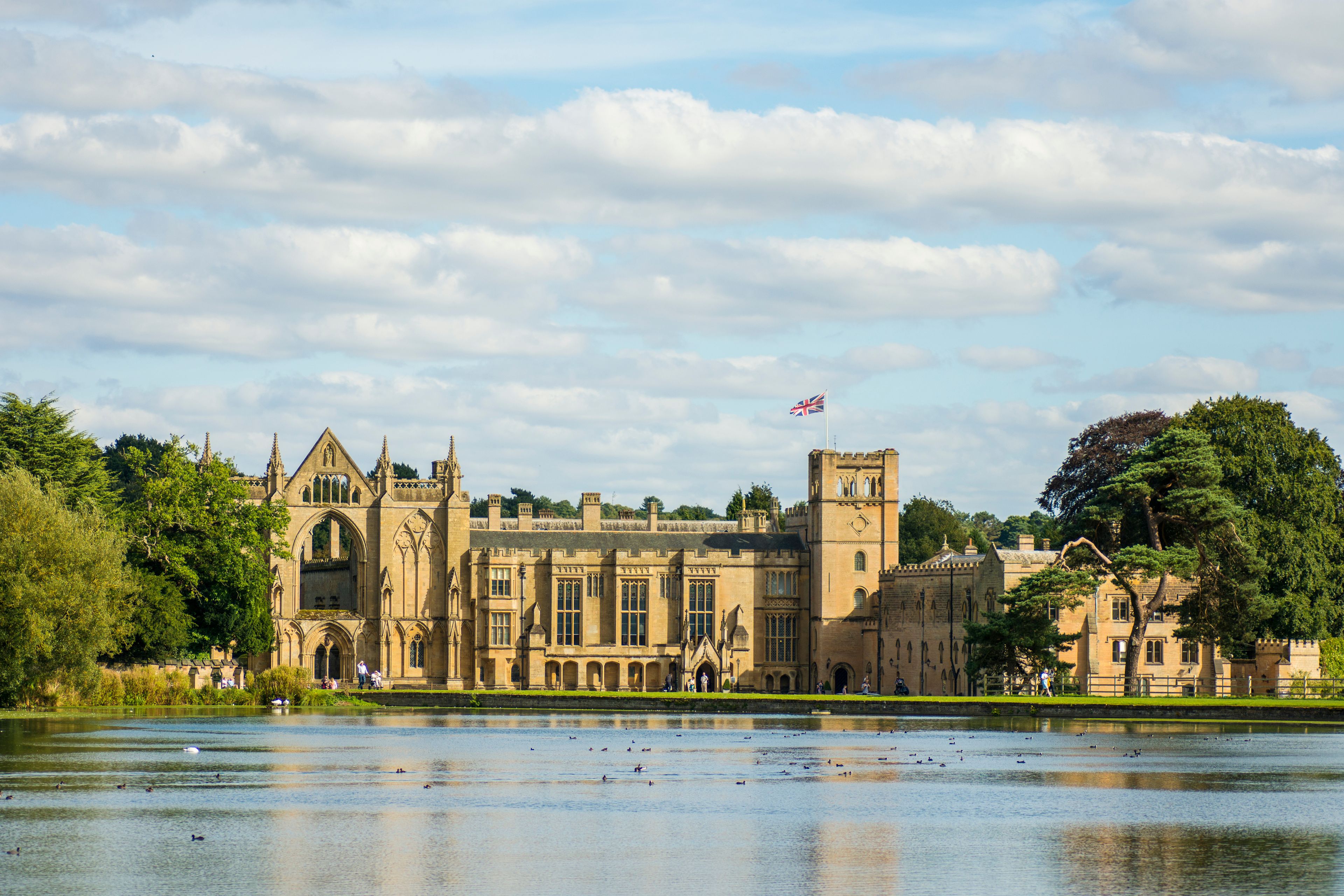 A historic building with a prominent clock tower, surrounded by a body of water and lush greenery.
