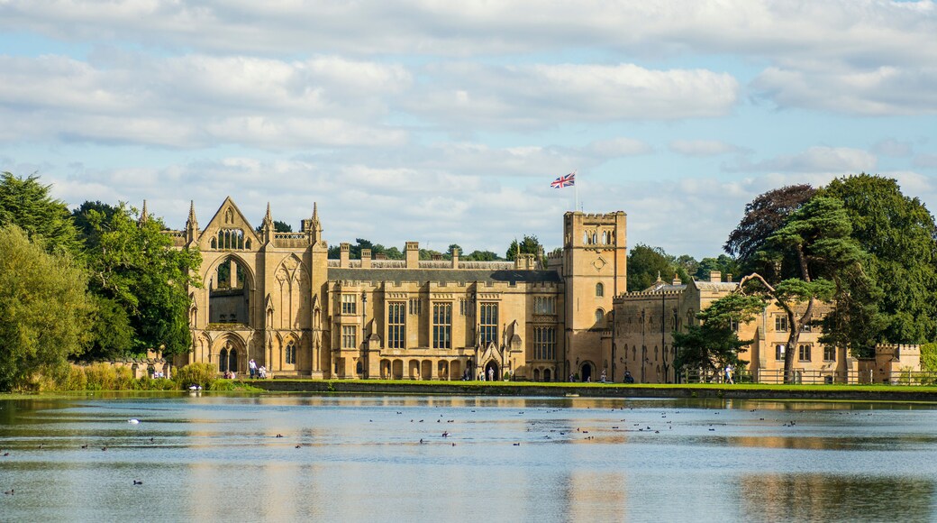 A historic building with a prominent clock tower, surrounded by a body of water and lush greenery.
