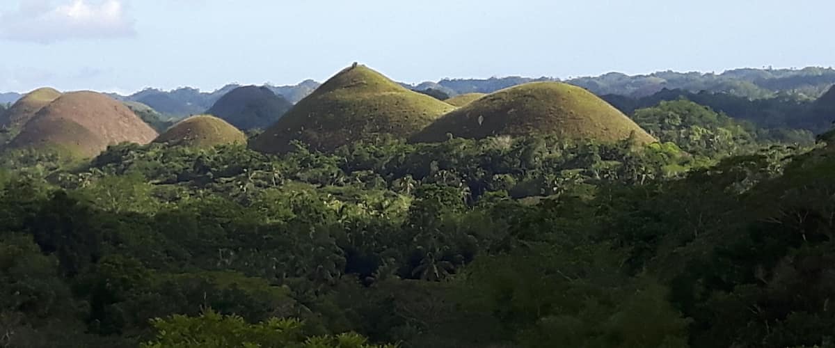 A landscape with multiple conical hills surrounded by dense green vegetation.
