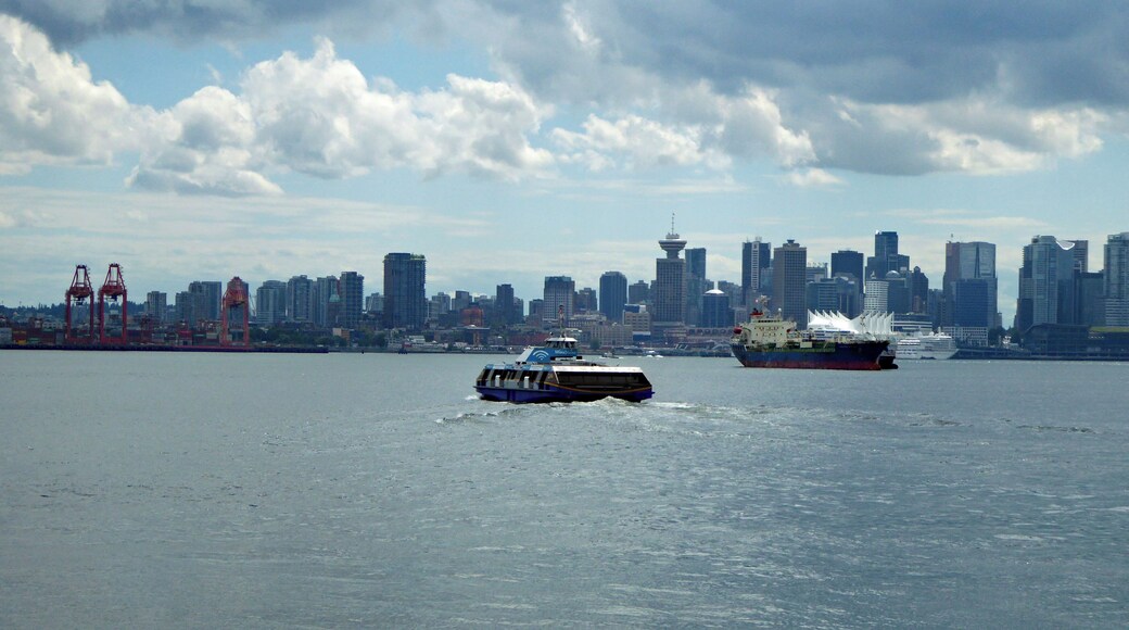 A Seabus heading toward downtown Vancouver crossing the Burrard Inlet on an overcast day. This is a regular passenger-only ferry service that crosses from Lonsdale Quay in North Vancouver to Waterfront Station in Vancouver. The journey takes around 10 to 12 minutes. This photo is taken from another Seabus looking back toward a Vancouver skyline.