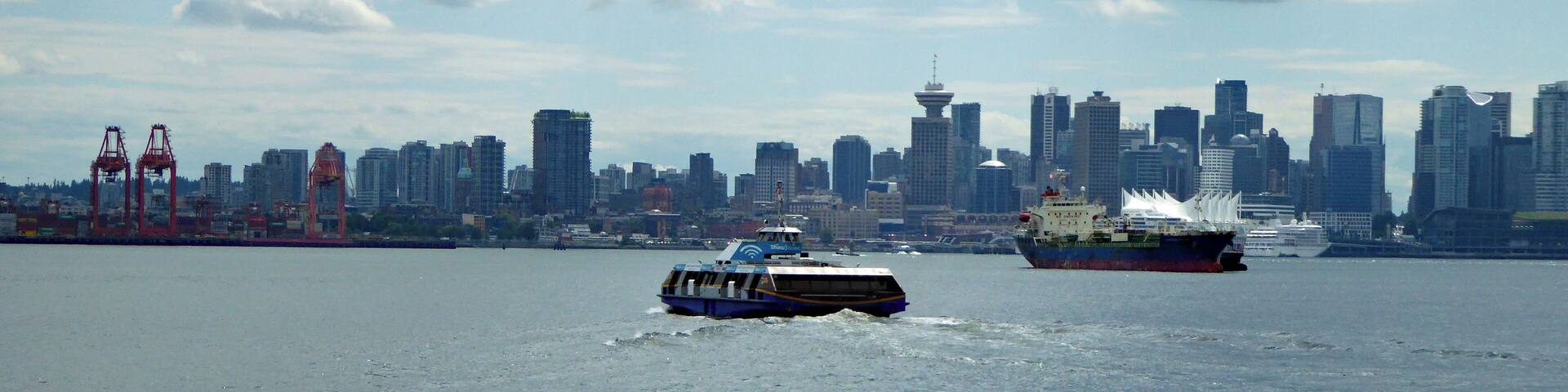 A ferry moving across a body of water with a city skyline in the background.