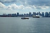 A Seabus heading toward downtown Vancouver crossing the Burrard Inlet on an overcast day. This is a regular passenger-only ferry service that crosses from Lonsdale Quay in North Vancouver to Waterfront Station in Vancouver. The journey takes around 10 to 12 minutes. This photo is taken from another Seabus looking back toward a Vancouver skyline.