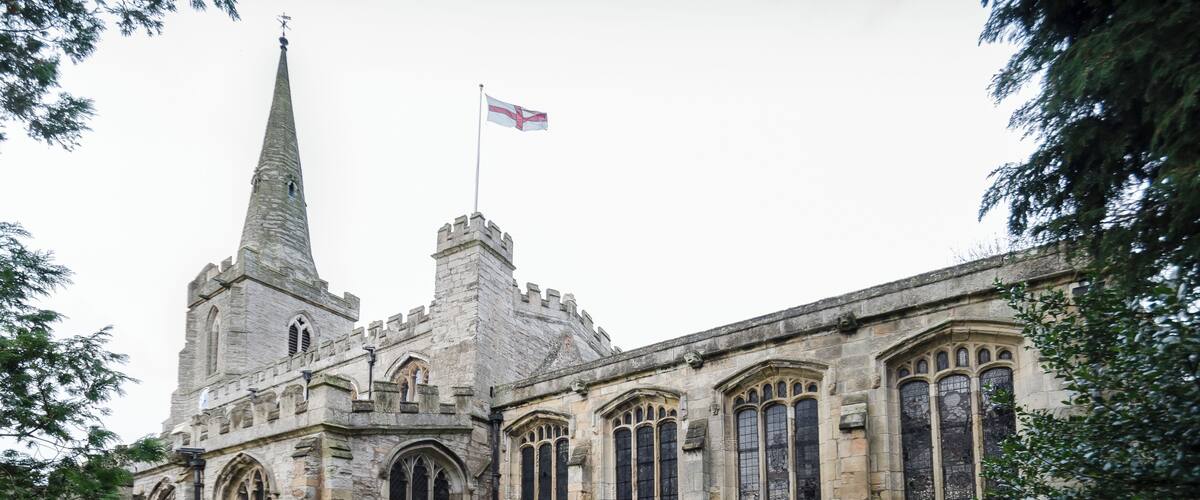 A historic stone church with a tall spire and a flag.