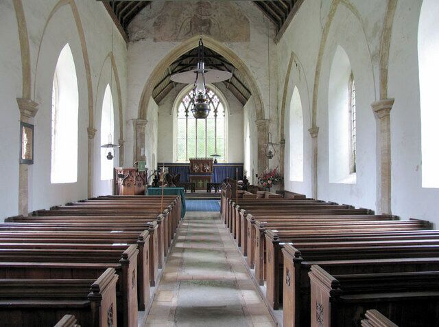 An interior of a church with wooden pews, arched windows, and a central altar.