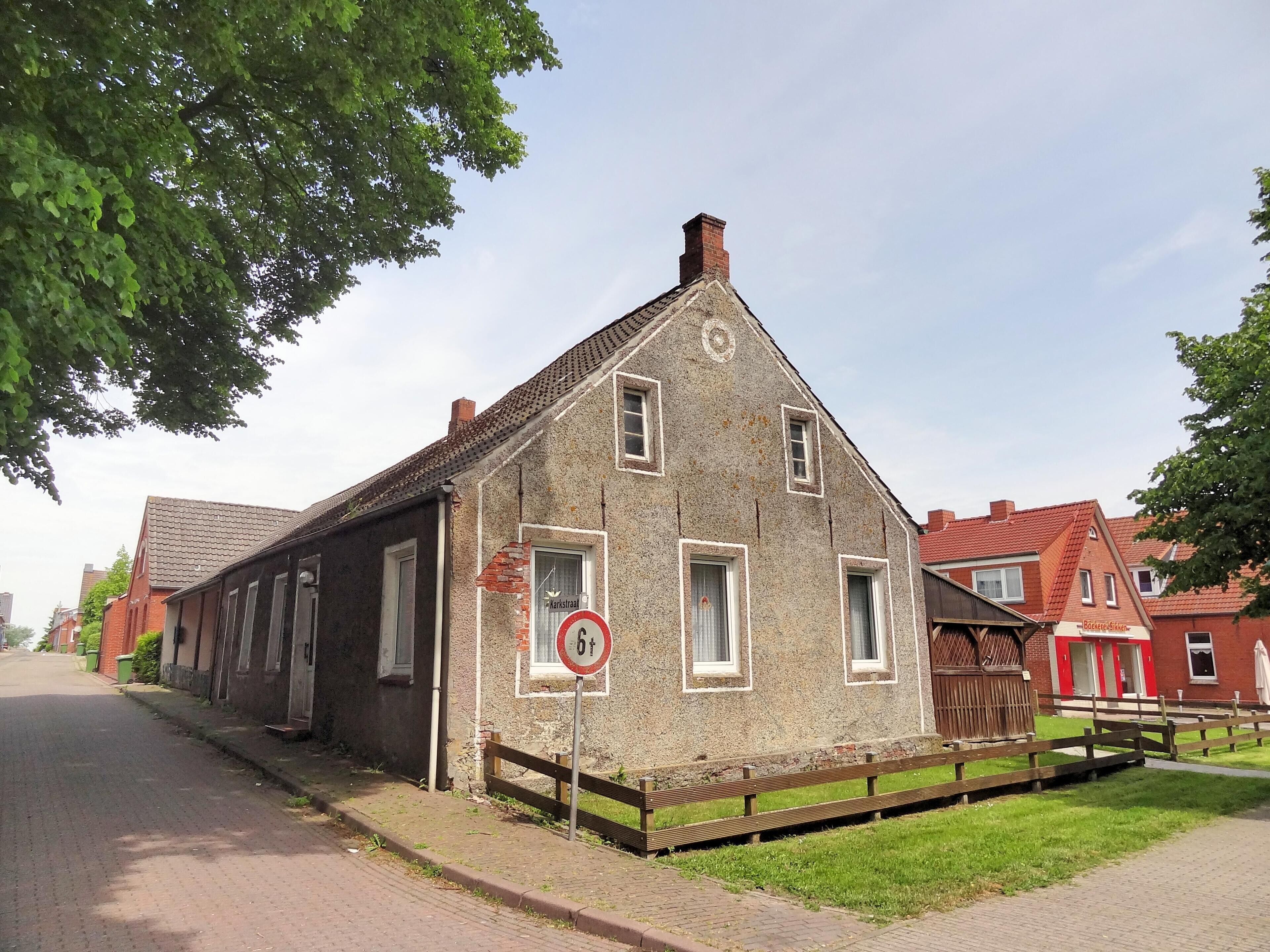 A historic building with a pointed roof, a brick chimney, and a 'no parking' sign.