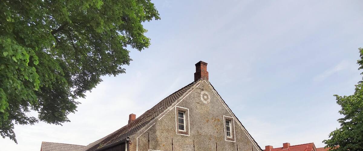 A historic building with a pointed roof, a brick chimney, and a 'no parking' sign.