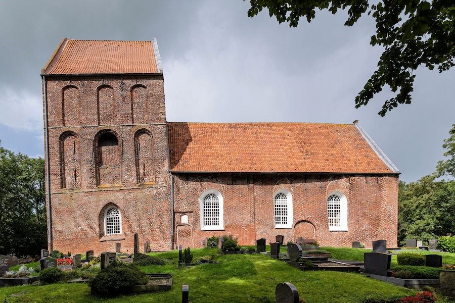 Une église en briques, dotée d’un haut clocher et de fenêtres en arc.