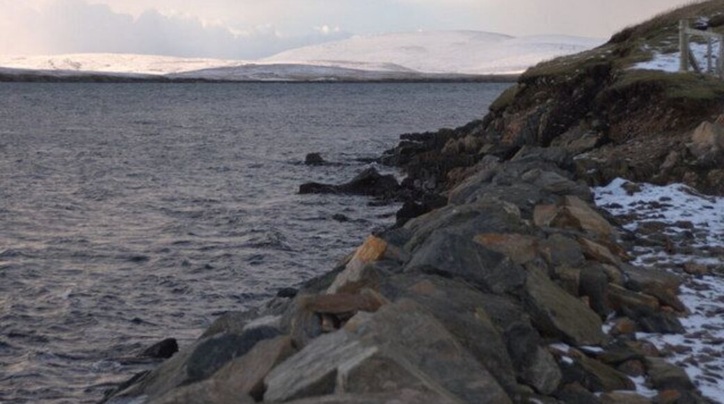 Coastline at Ulsta In the foreground are the reinforcements for the coast beside the Yell Sound ferry terminal at Ulsta. In the background, is a snow-covered Ronas Hill, the highest point in Shetland at 450m.