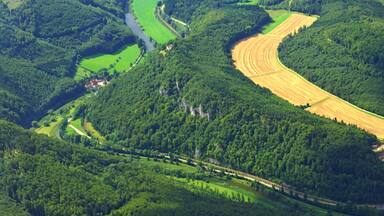 A river winding through a valley with dense forests and agricultural fields.