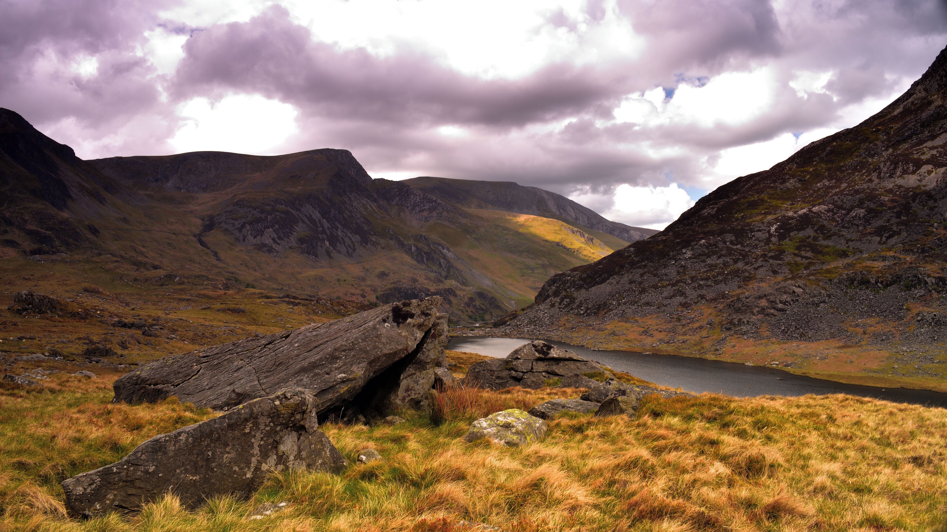 A mountainous landscape with a lake, rocky terrain, and grassy areas.