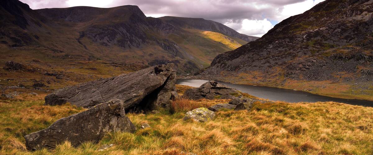 A mountainous landscape with a lake, rocky terrain, and grassy areas.