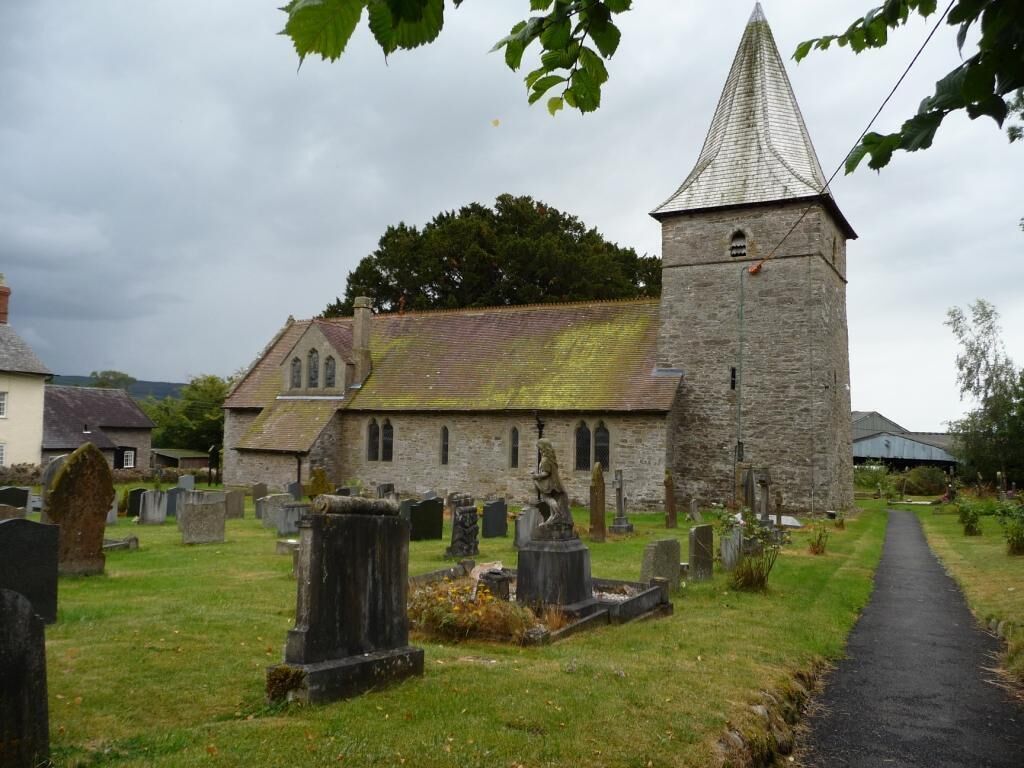 A church with a stone tower and a graveyard.