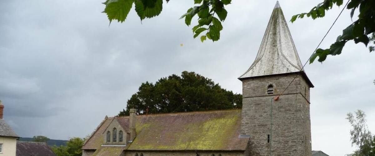 A church with a stone tower and a graveyard.