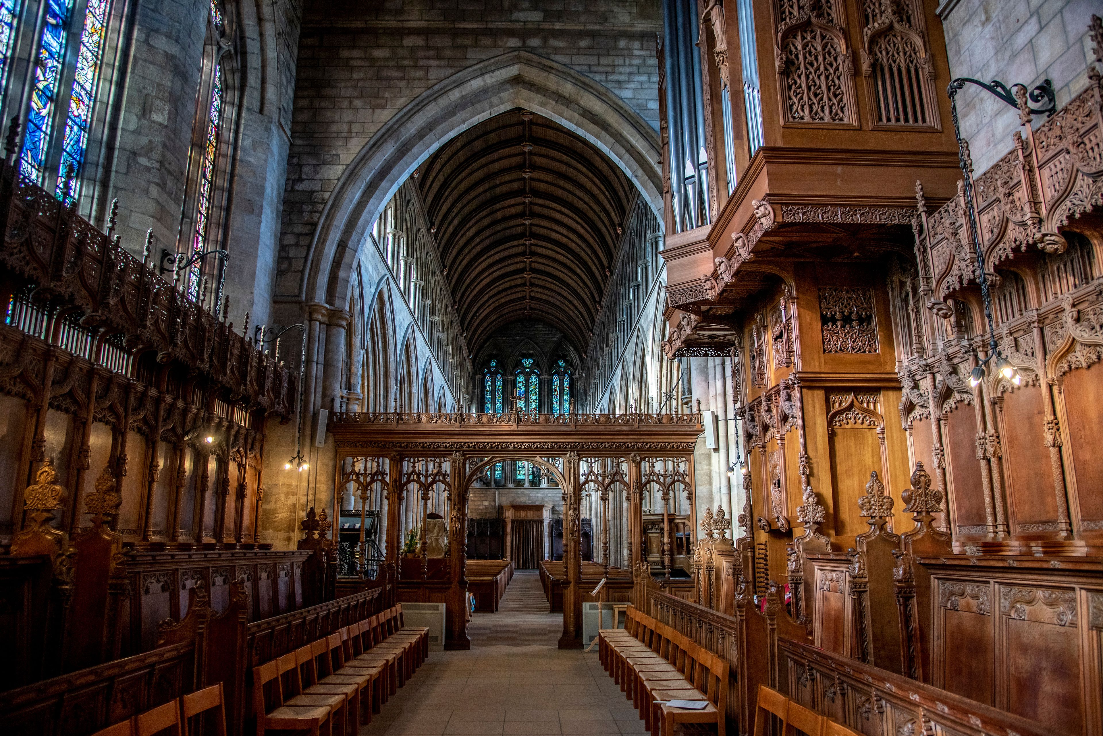An interior of a cathedral with Gothic architecture, including pointed arches, ribbed vaults, and stained glass windows.
