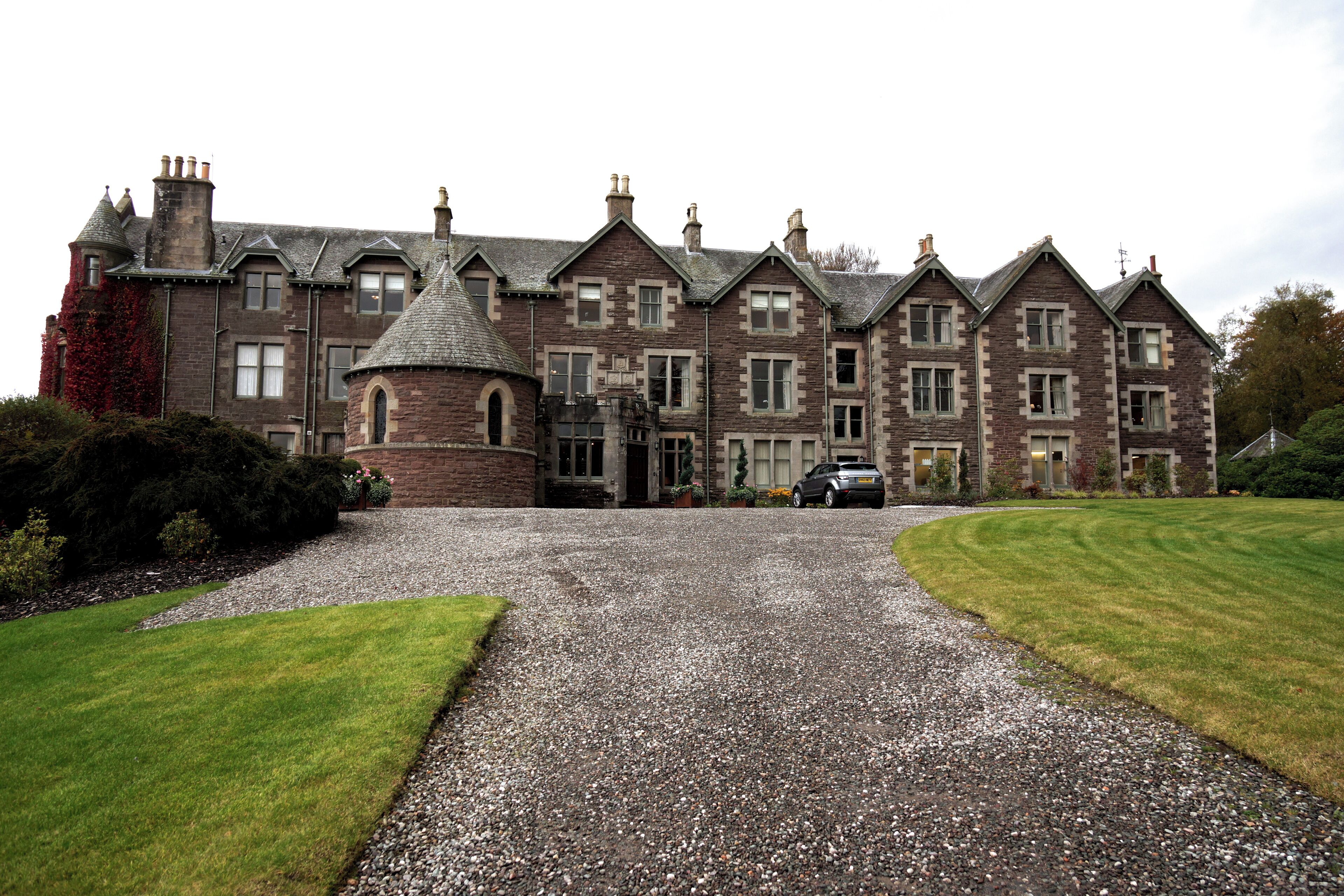 A large, historic stone building with multiple chimneys and a prominent turret.