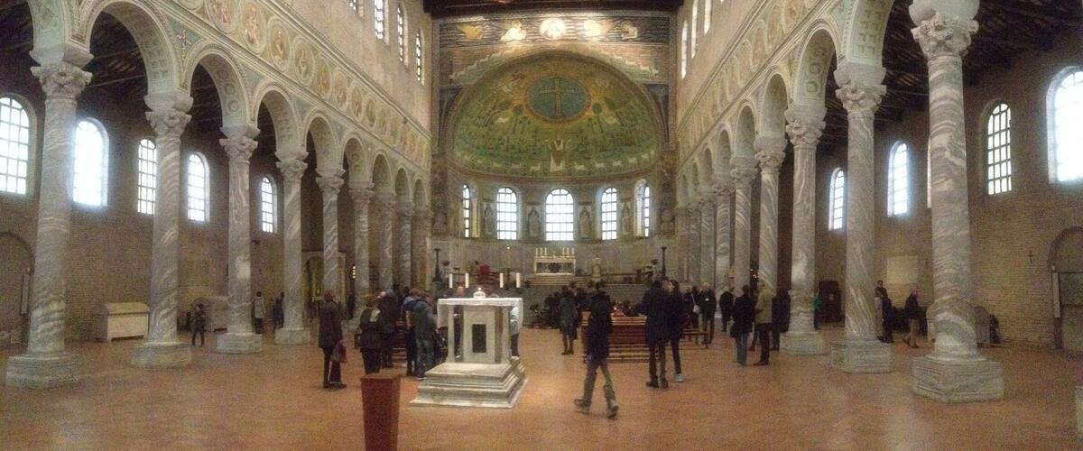 An interior with a high vaulted ceiling, arched columns, and a central altar.