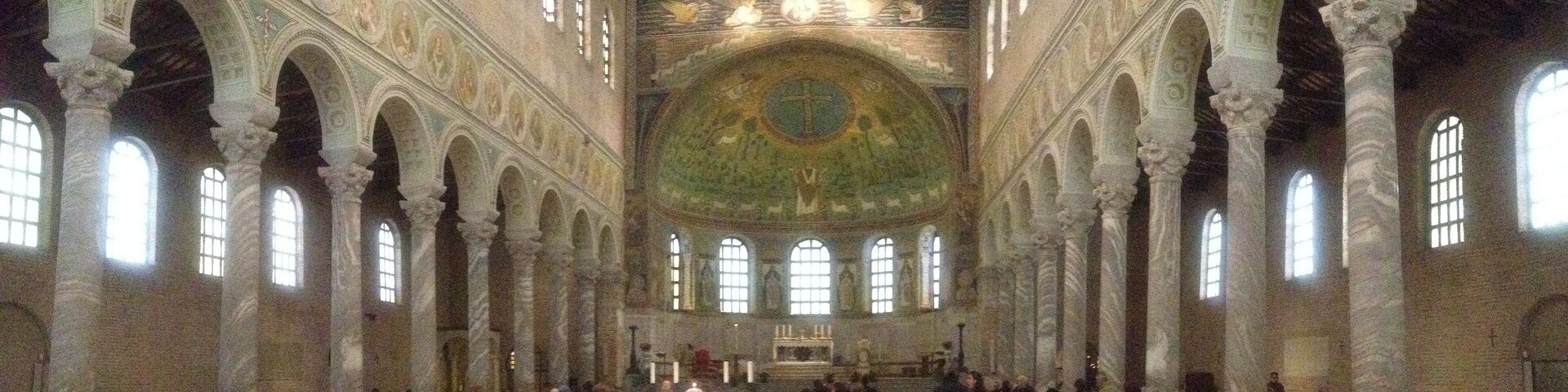 An interior with a high vaulted ceiling, arched columns, and a central altar.
