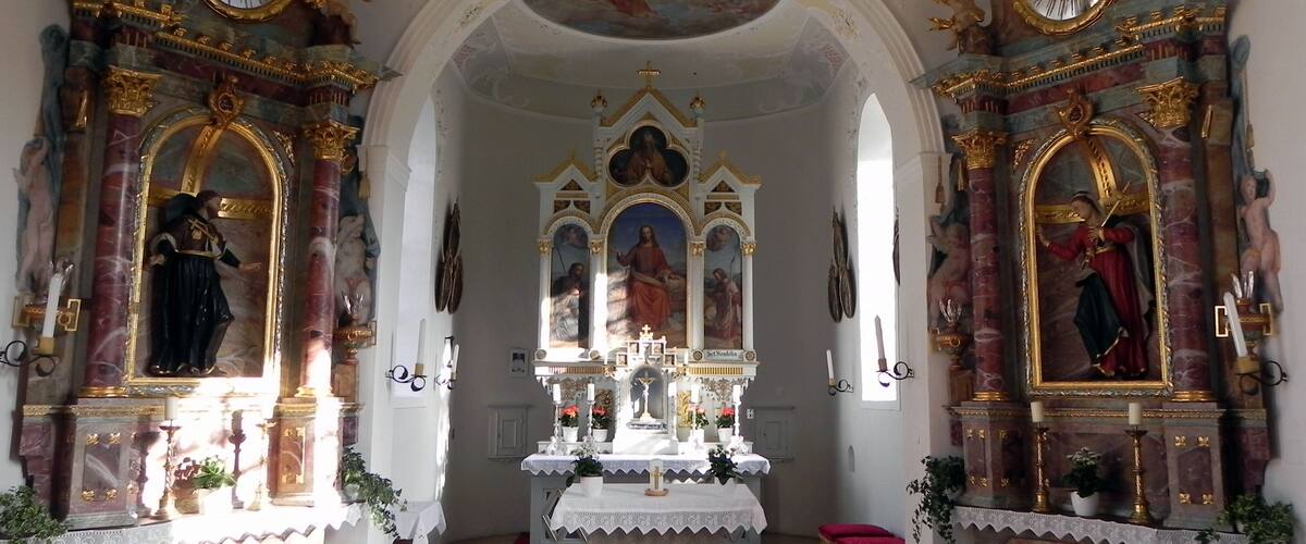 An ornate church interior with religious statues, a central altar, and detailed ceiling artwork.