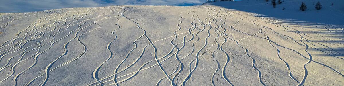 Aerial view of beautiful Auron winter sports resort with snow-covered ski tracks and serene mountains, Alpes Maritimes, France.