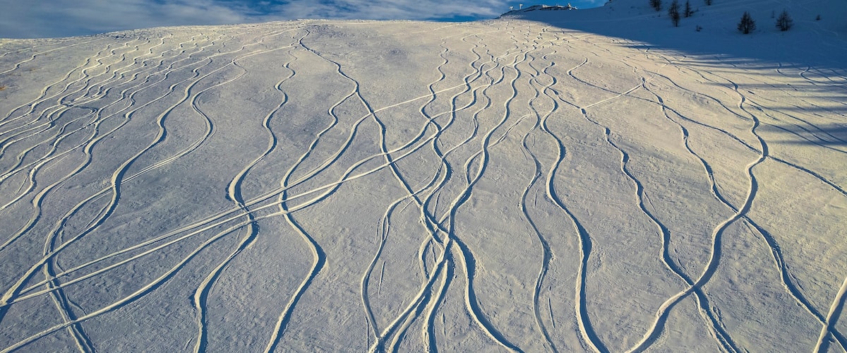 Aerial view of beautiful Auron winter sports resort with snow-covered ski tracks and serene mountains, Alpes Maritimes, France.