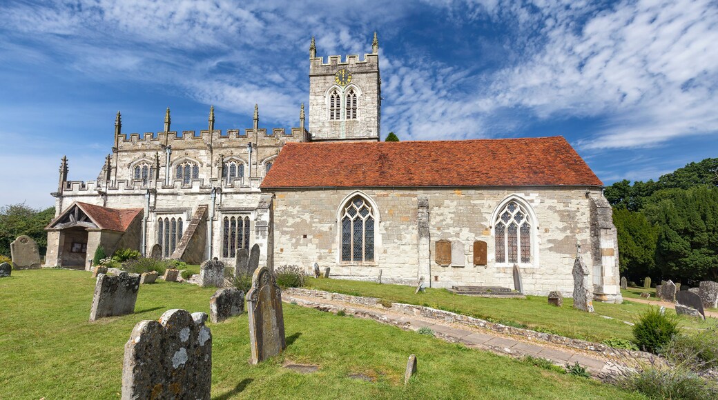 A historic church with a red-tiled roof, stone walls, and a clock tower.