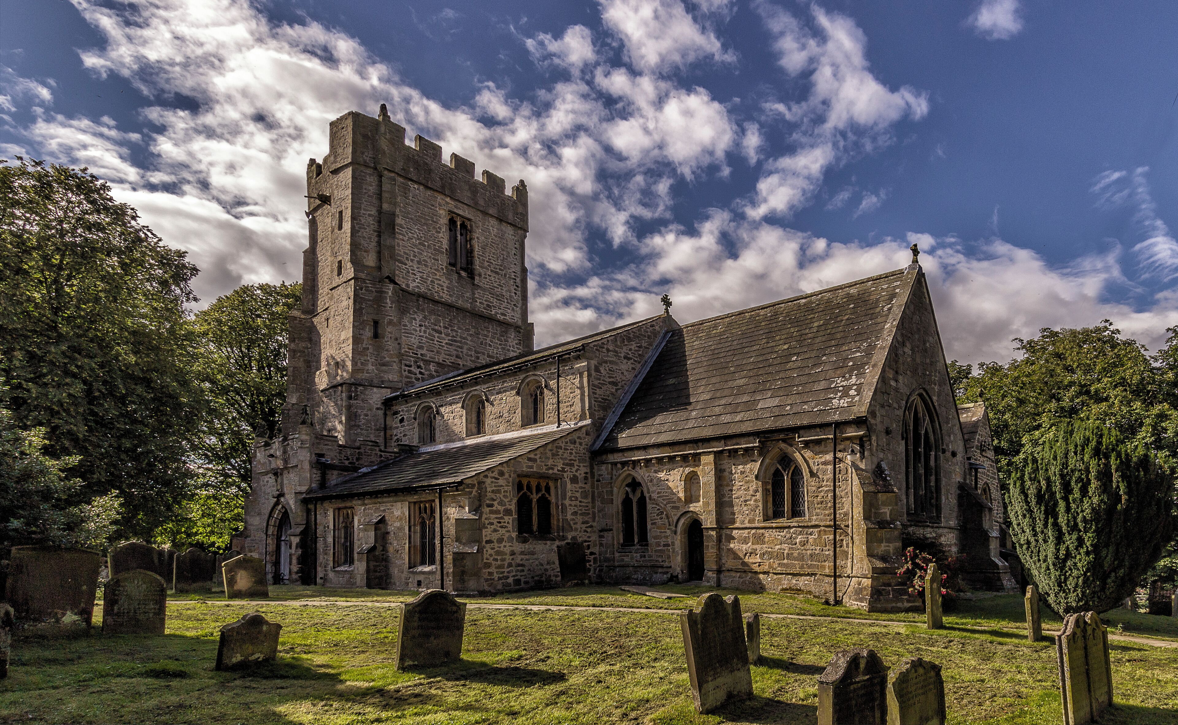 A historic stone church with a tall tower and arched windows.