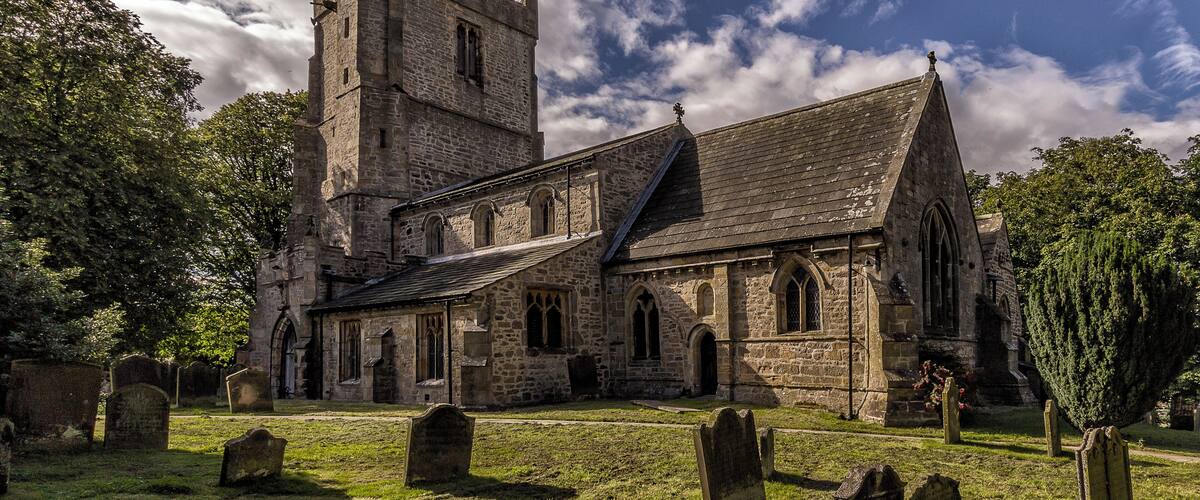 A historic stone church with a tall tower and arched windows.