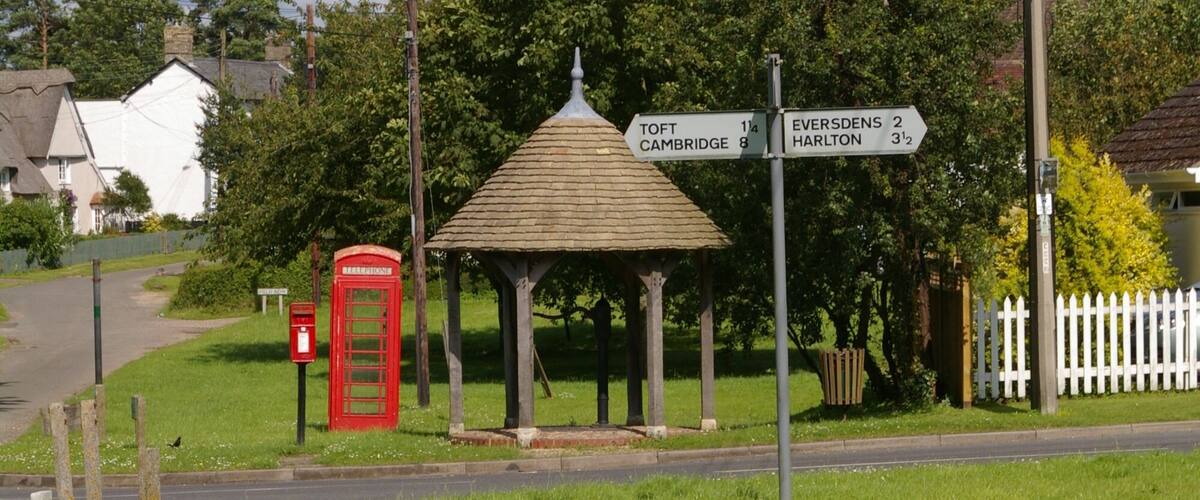 A gazebo, a red telephone booth, and directional signs for nearby towns.