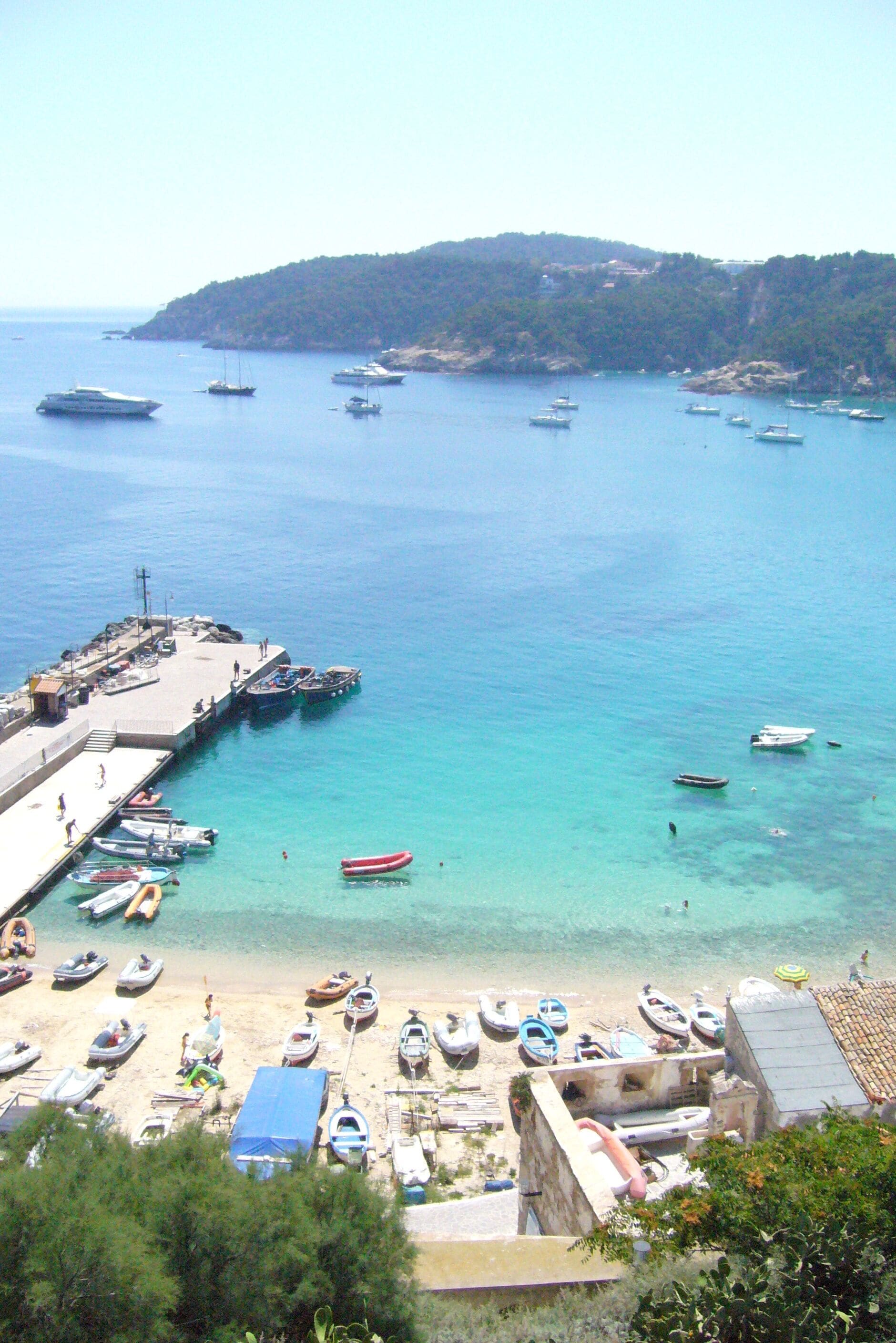 A coastal scene with a pier, boats, and a beach.