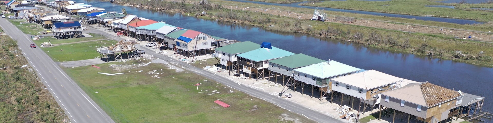 Aerial view of colorful stilt houses lining the waterway, beside the asphalt road, Delacroix, Louisiana, United States.