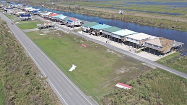 Aerial view of colorful stilt houses lining the waterway, beside the asphalt road, Delacroix, Louisiana, United States.