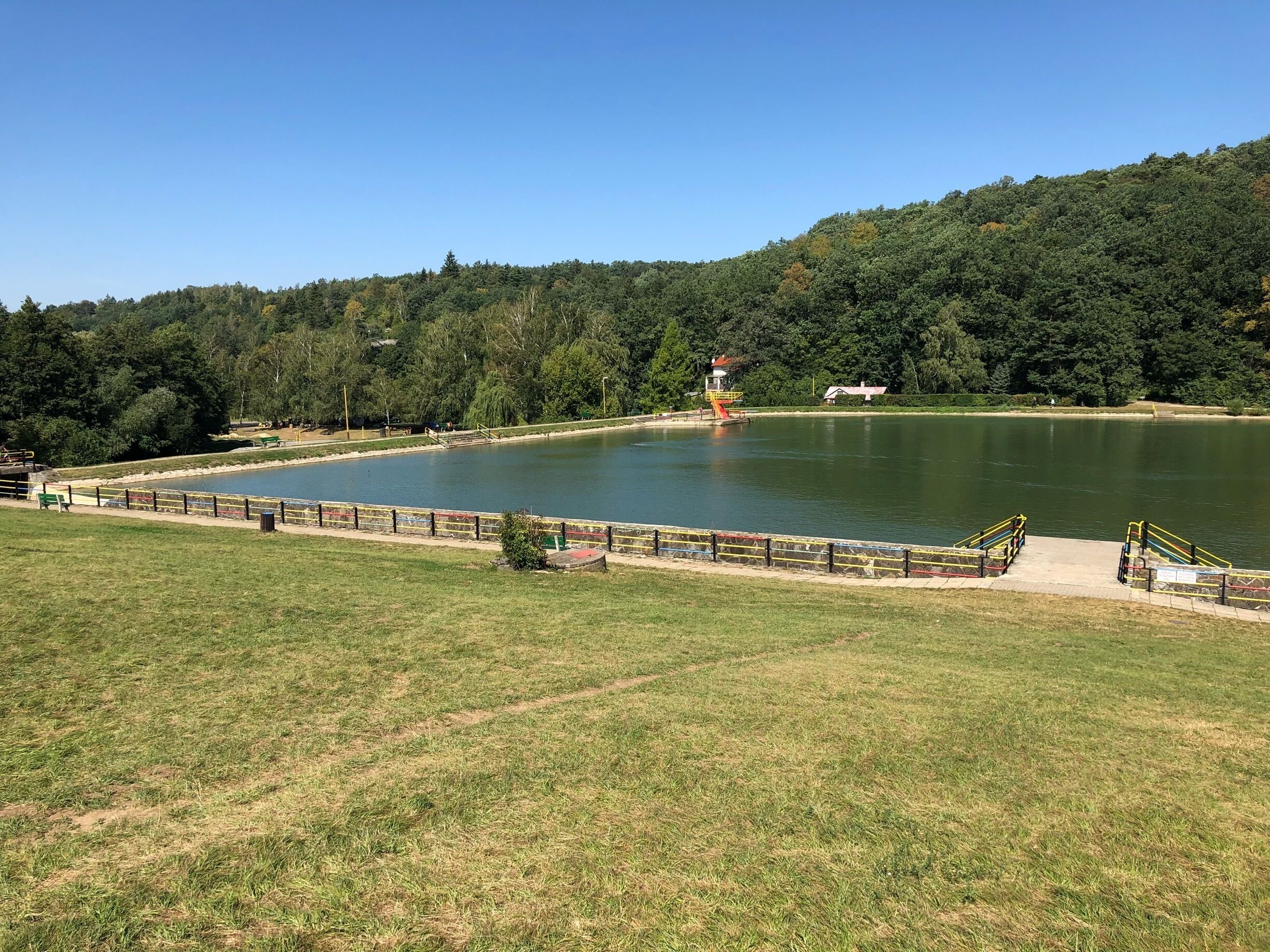 A lake surrounded by a grassy area with a small building and a bridge.
