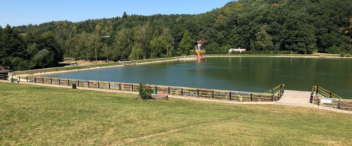 A lake surrounded by a grassy area with a small building and a bridge.