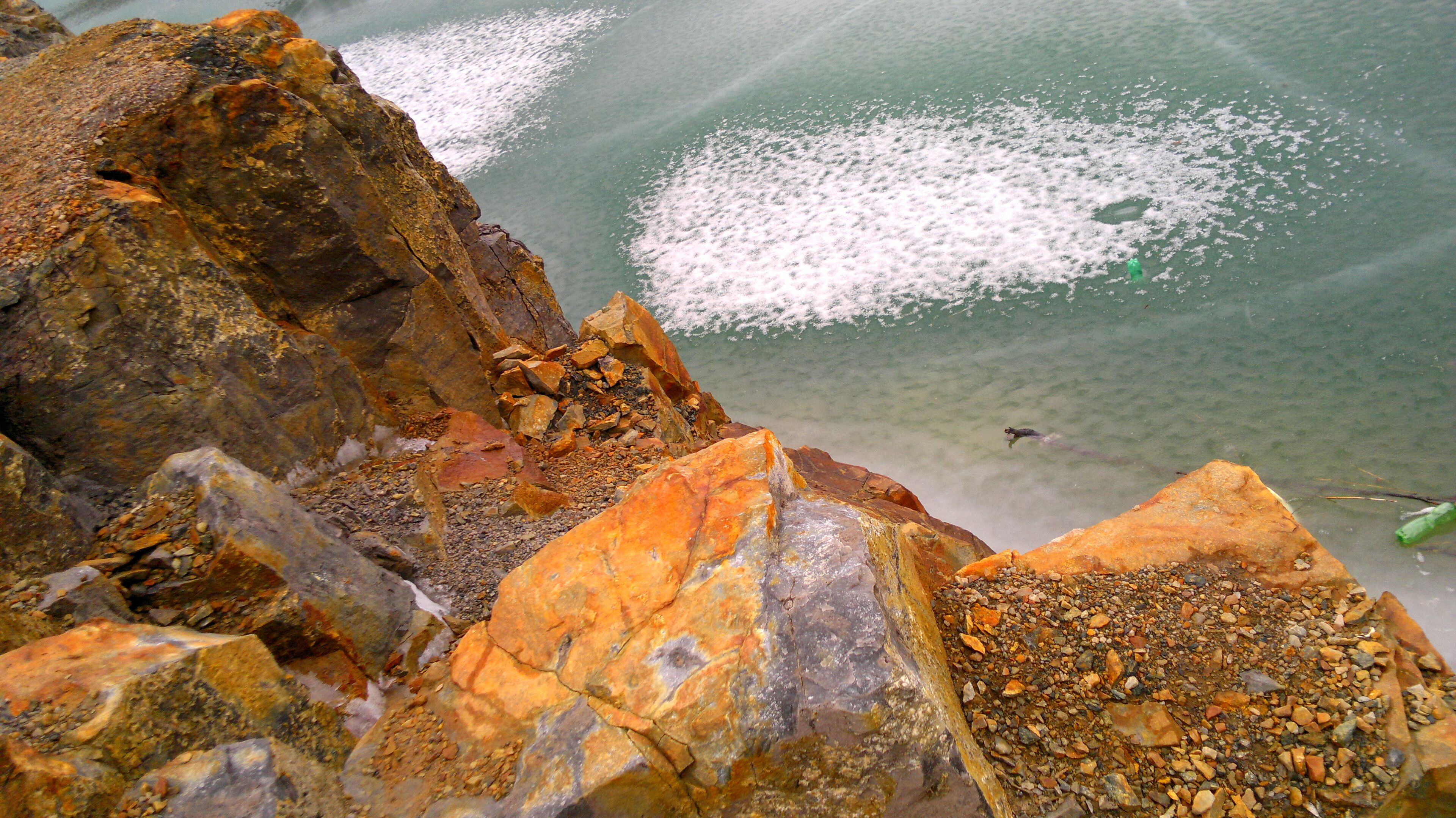 A rocky shoreline with clear water and a person swimming.