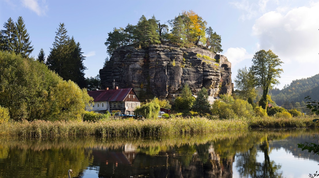 A house on a cliff by a calm river with reflections.