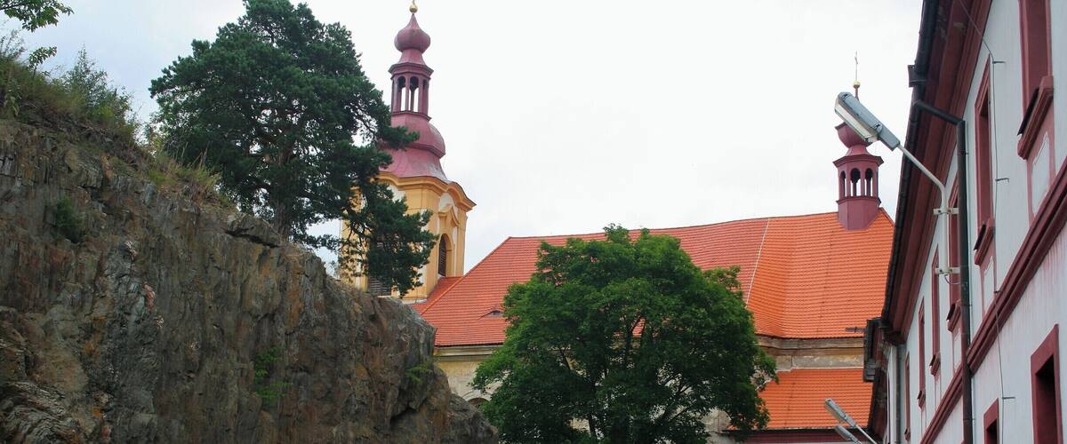 A rocky cliff, a building with red-tiled roof, and a person walking a dog.