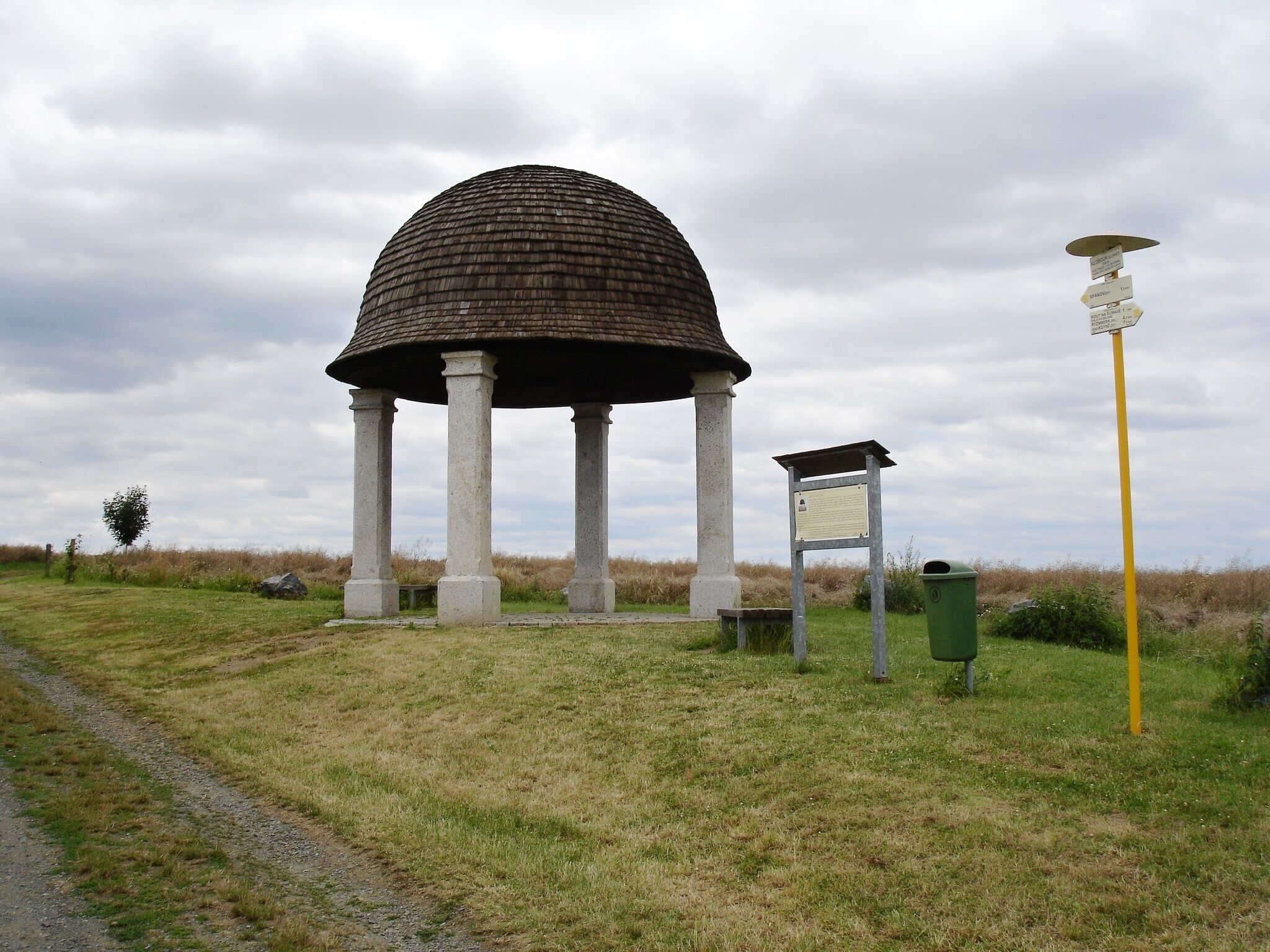 A gazebo with a dome roof and columns, surrounded by grass and a path.