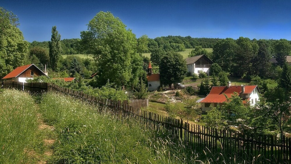 A rural village with houses, a church, and a wooden fence.