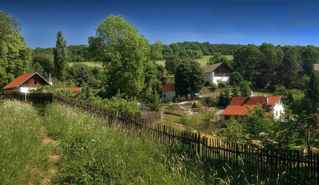 A rural village with houses, a church, and a wooden fence.