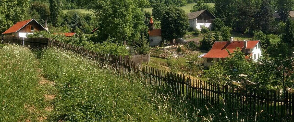 A rural village with houses, a church, and a wooden fence.